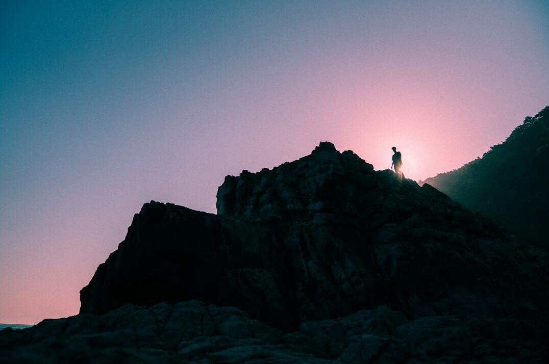 person climbing mountain at dawn